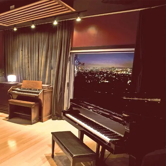 A piano in front of a large screen tv.