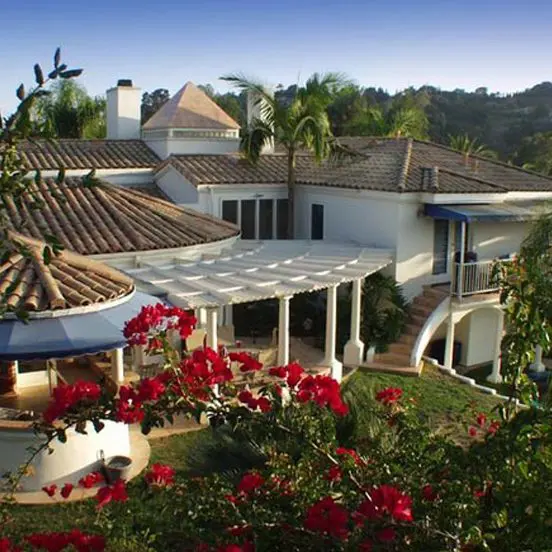 A large white house with red flowers in the foreground.